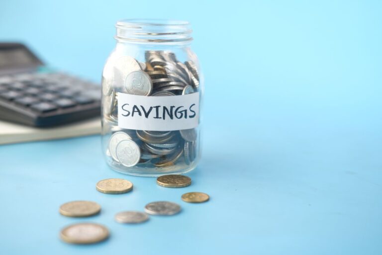 Glass savings jar filled with coins on a table